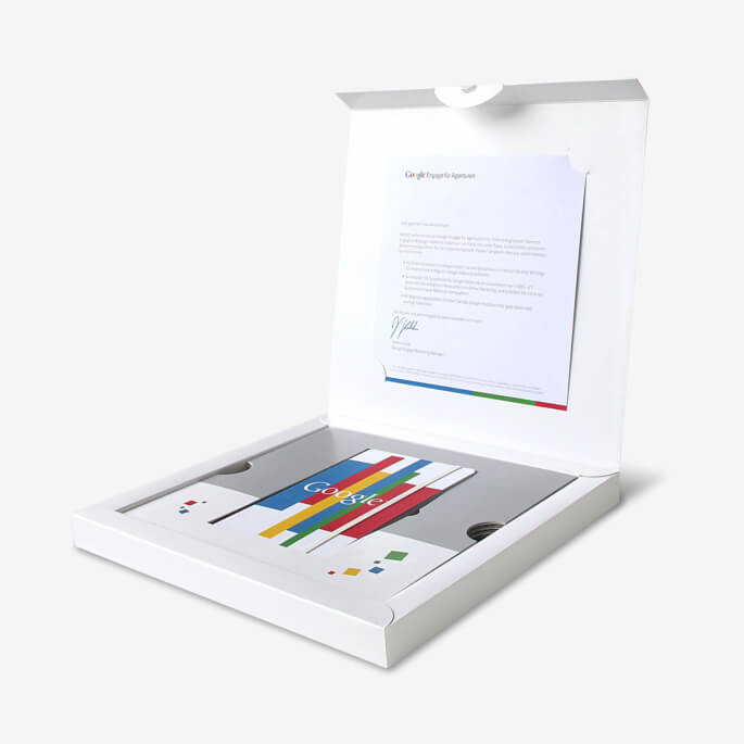 Aufgeklappter Umkarton eines Mailings mit Anschreiben und Giveaway